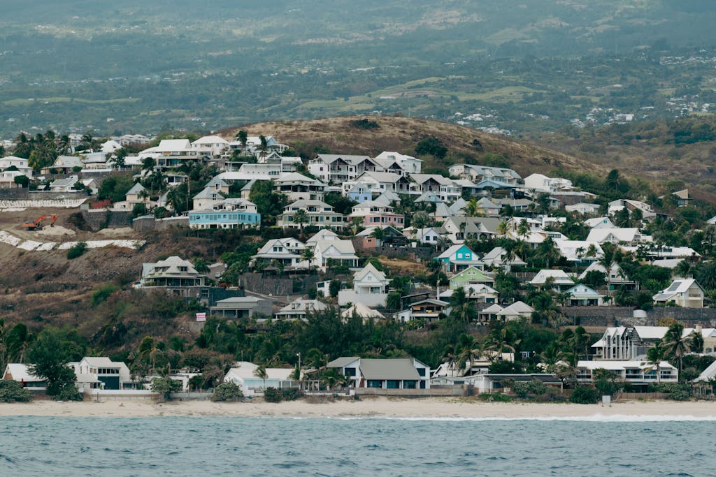 A picturesque coastal town on La Réunion Island, showcasing hillside homes near the ocean.